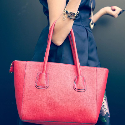 A woman holding onto her purse while wearing a watch.