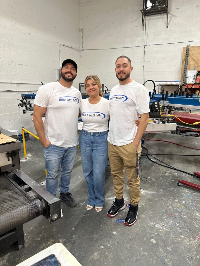 Three people standing in a room with some machines