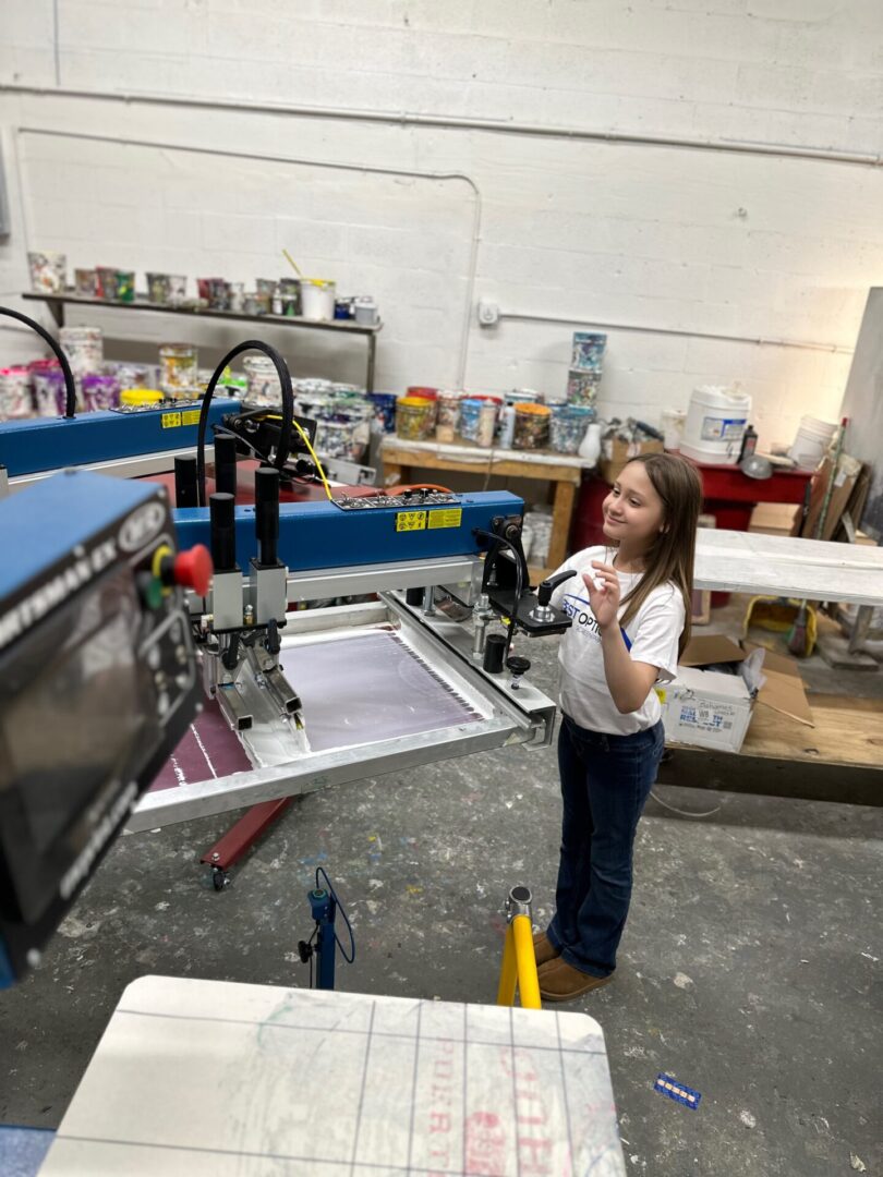 A girl standing in front of a machine.