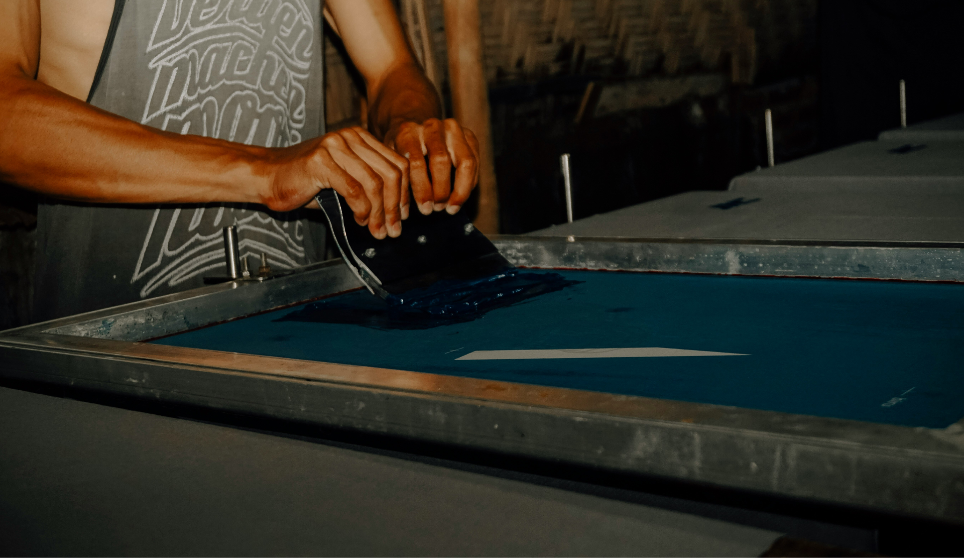 A person using a large screen printing machine.