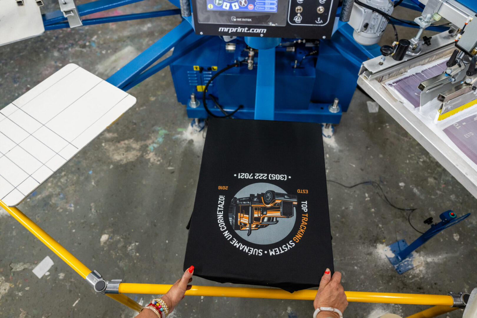 A person is holding onto the screen printing machine.