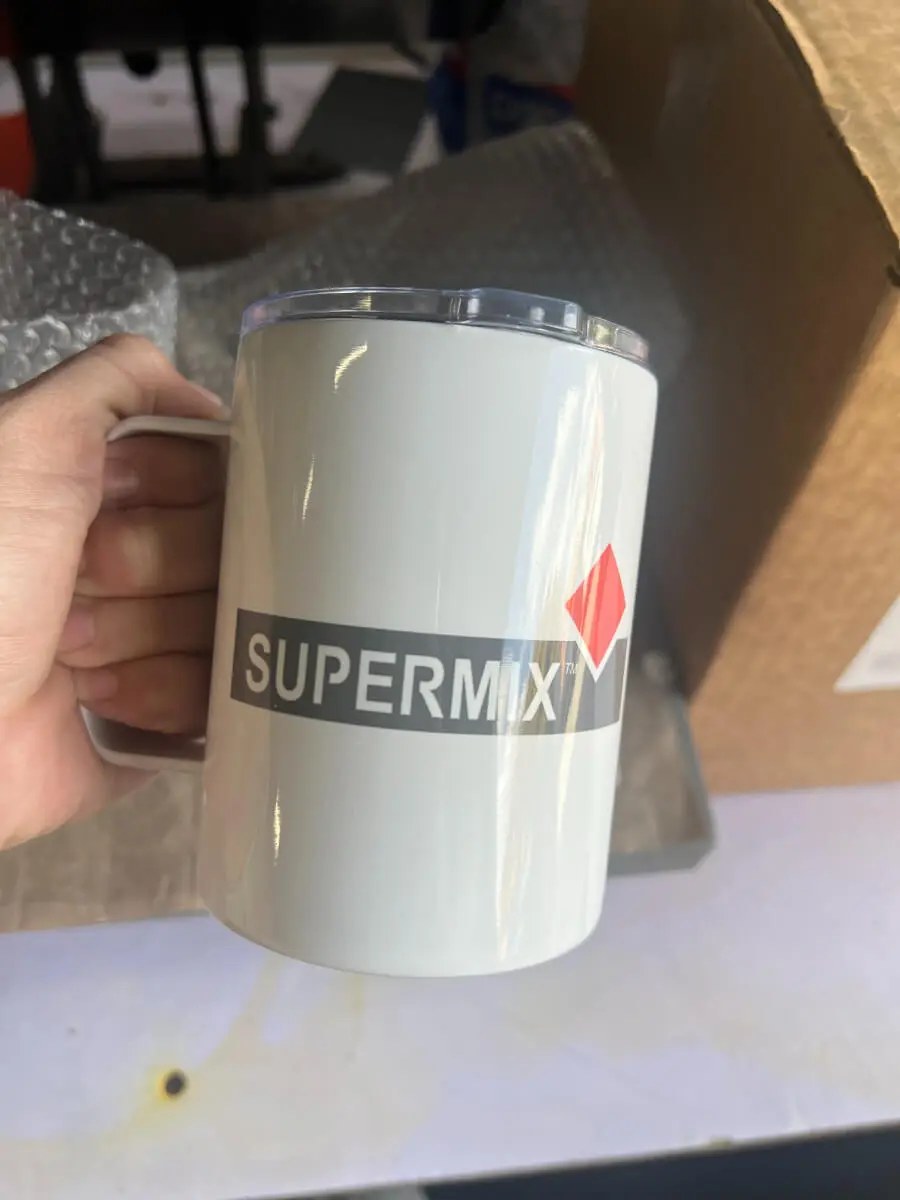 A person holding up a cup with supermix on it.