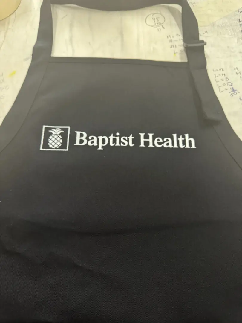 A black apron with the baptist health logo on it.