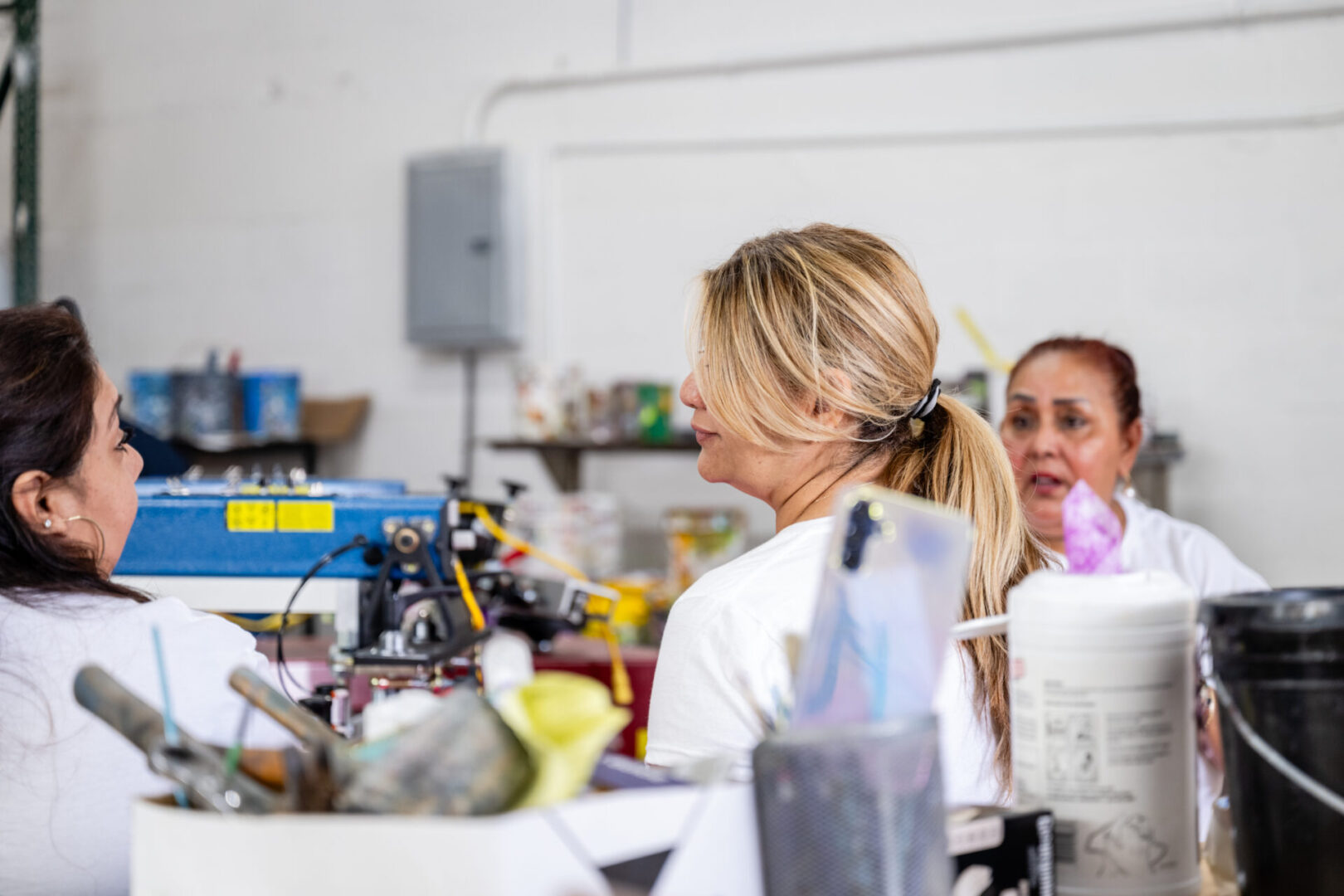 Two women sitting at a table in front of a machine.