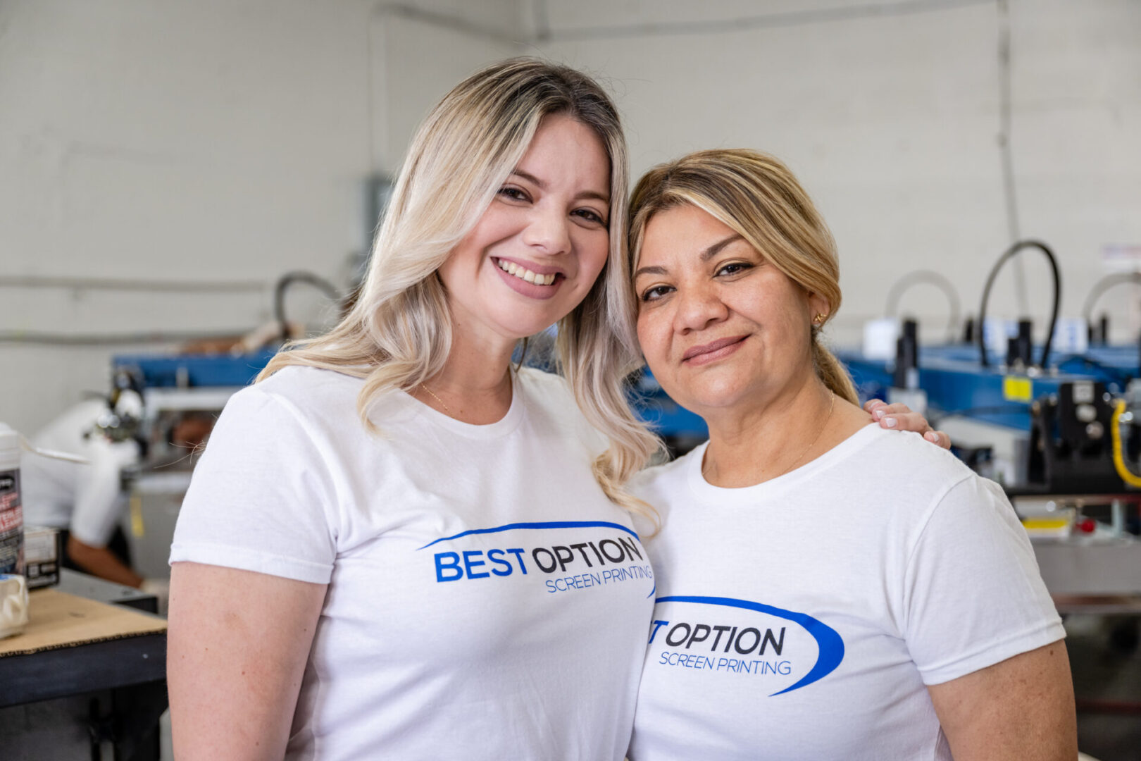 Two women wearing white shirts and smiling for a picture.