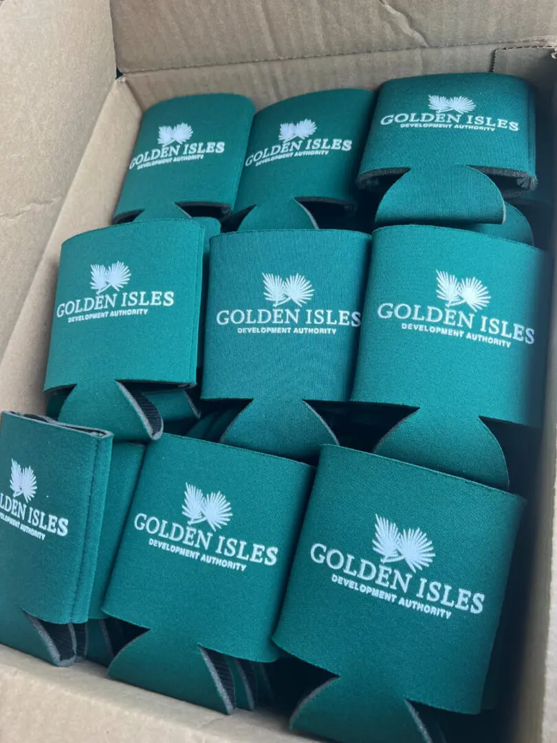 A box of green koozies with the golden isles logo on them.