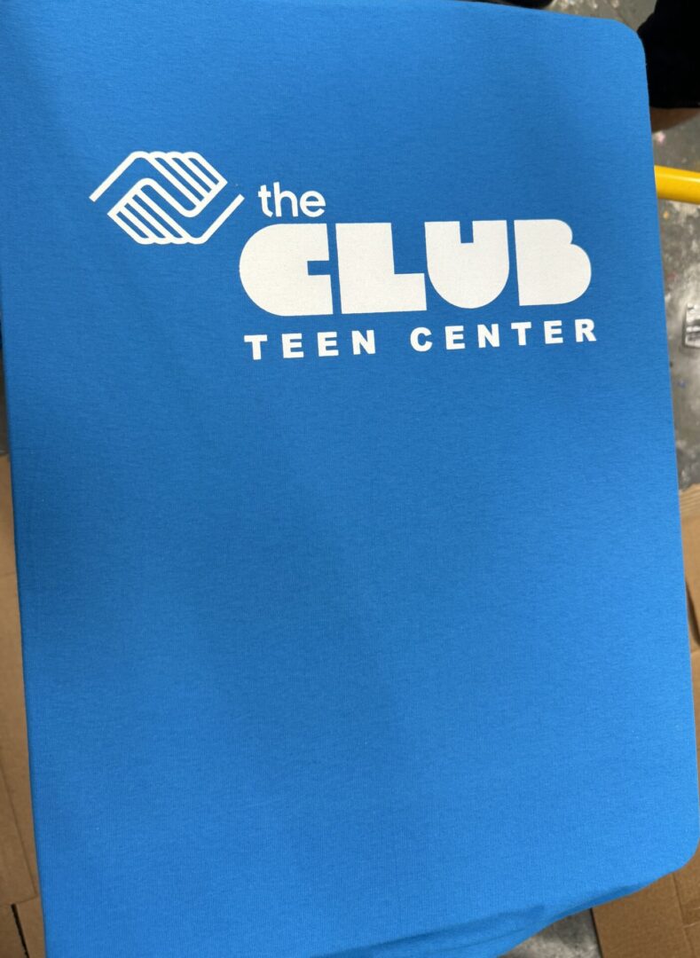 A blue folder with the club teen center logo on it.